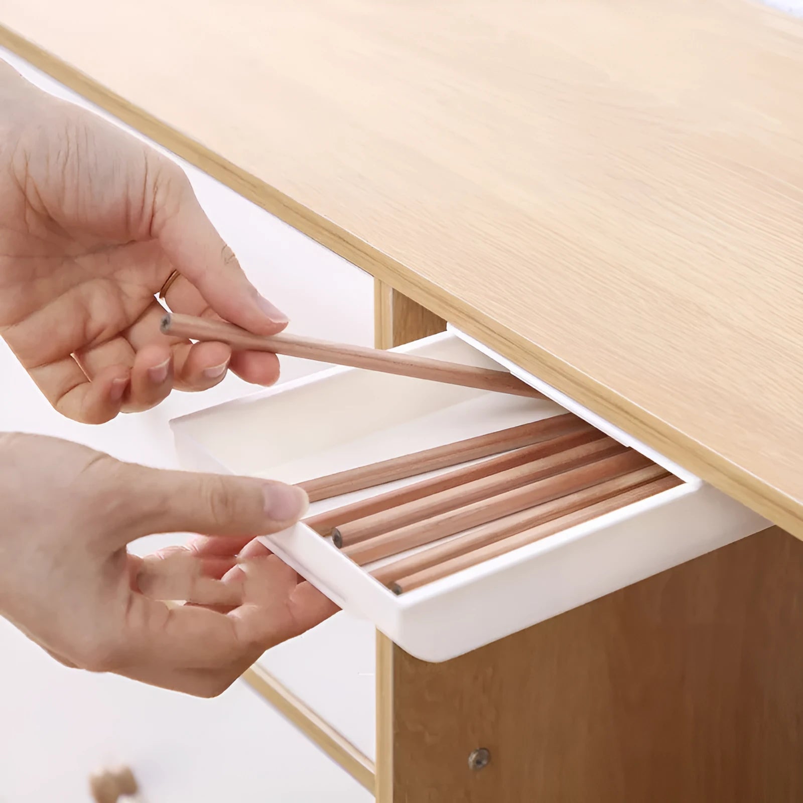 Grey Japanese style plastic drawer storage box placed under a table with stationery inside
