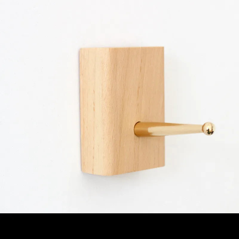 Modern beech wood adhesive wall hook with brass hook in capsule shape.