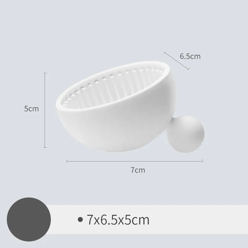 Small silicone makeup brush cleaning scrub tray in white with raised textured centre for removing foundation residue