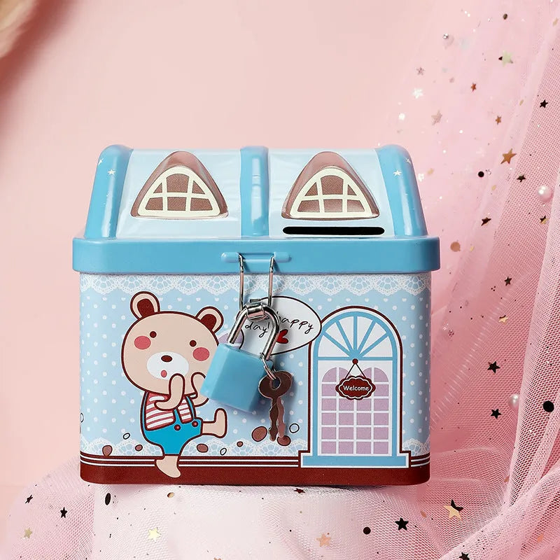 Blue and pink house-shaped tinplate piggy bank for coins on a wooden desk.