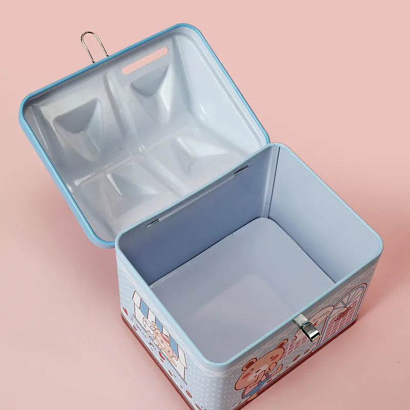 Blue and pink house-shaped tinplate piggy bank for coins on a wooden desk.