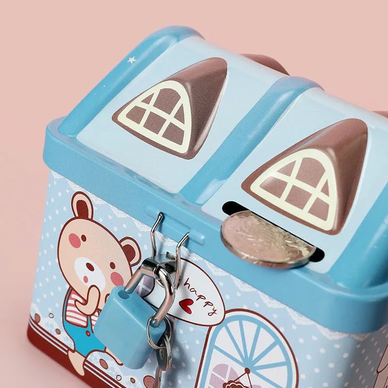 Blue and pink house-shaped tinplate piggy bank for coins on a wooden desk.