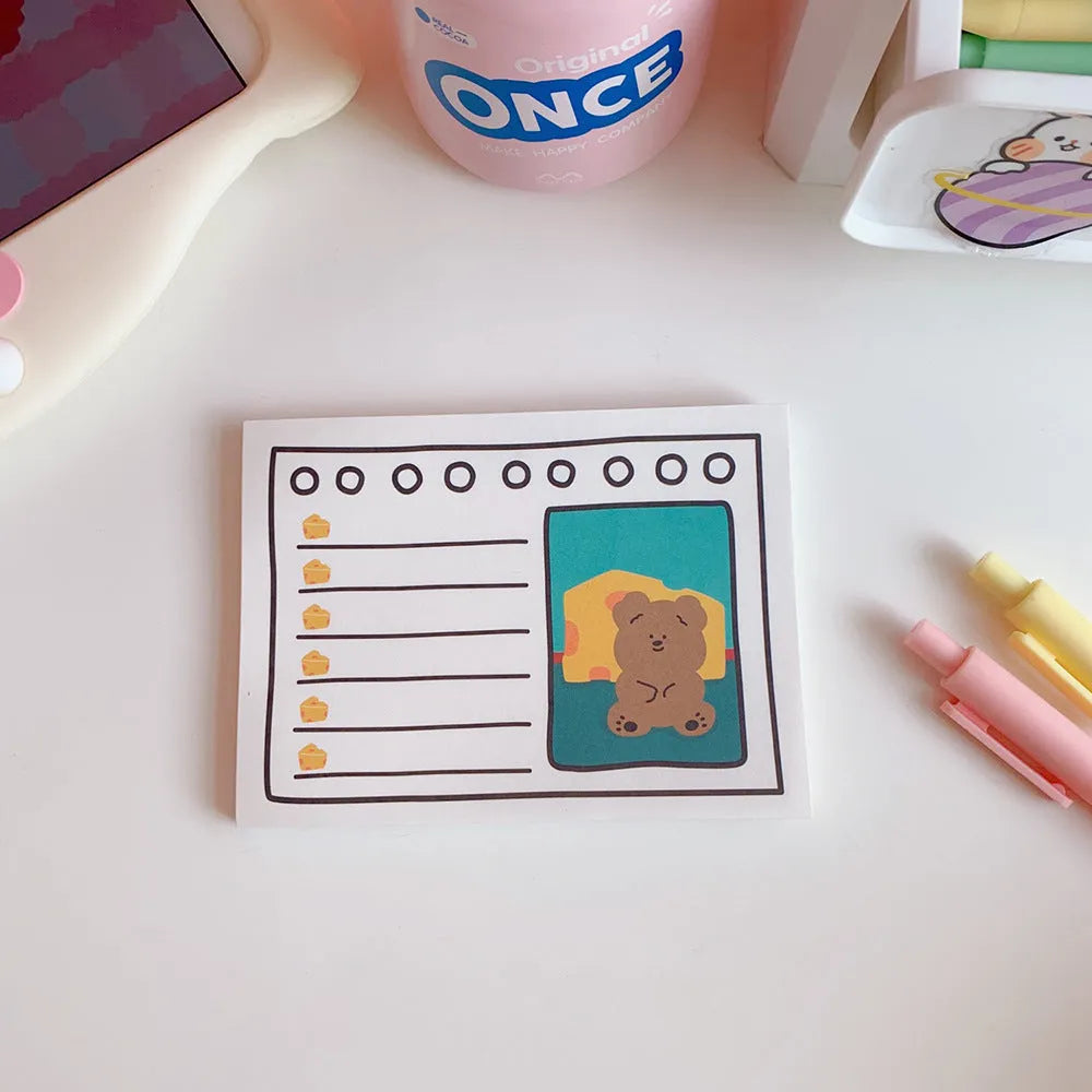 Kawaii bear cartoon design memo pad notebook open on a desk with a pen.