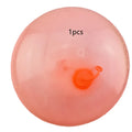 Large pink, yellow, green, and blue inflatable bouncy balls in different sizes for outdoor play.