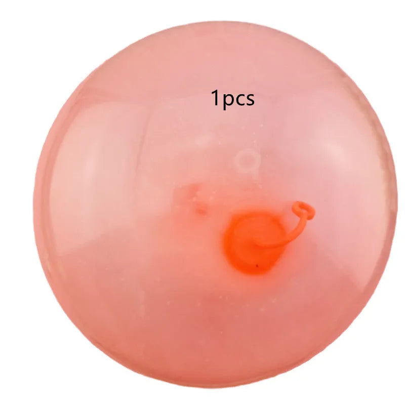 Large pink, yellow, green, and blue inflatable bouncy balls in different sizes for outdoor play.