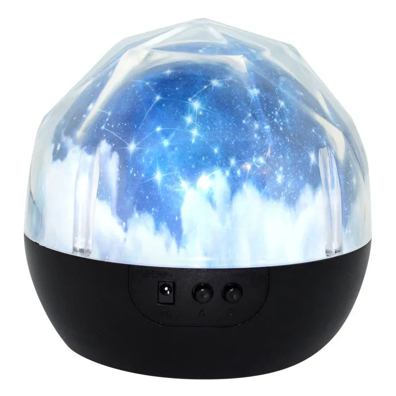 Compact white starry sky projector on a table, projecting blue constellation patterns onto a dark wall.