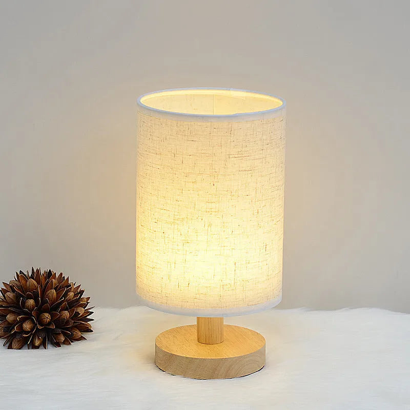 Solid wood cloth cover LED table lamp with grey linen shade and USB cable on a wooden desk