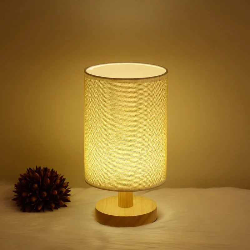 Solid wood cloth cover LED table lamp with grey linen shade and USB cable on a wooden desk