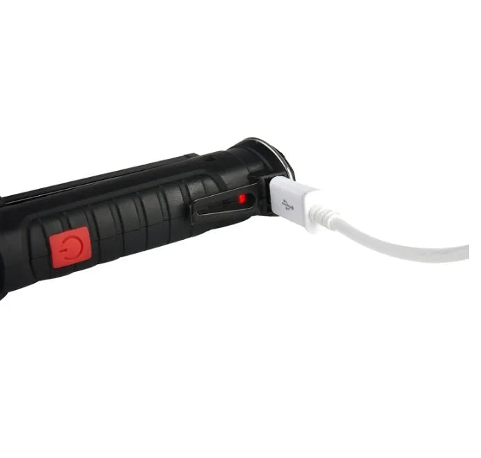 COB LED tactical flashlight in carbon-black finish with folding stand, magnet, and hanging hook on a metal surface