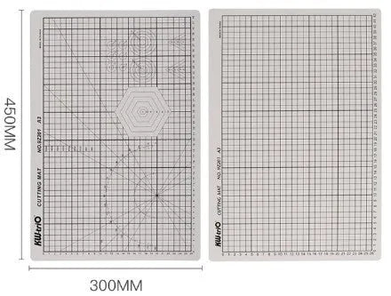 Green A3 self-healing cutting mat with centimetre grid lines on a desk.