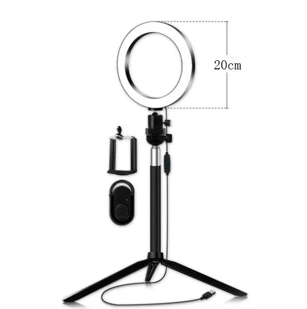 Black 20cm LED ring light kit with tripod, selfie stick, and phone clip on a desk