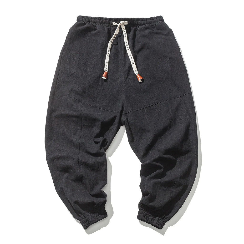 Men's cotton harem joggers in black with drawstring waist, two slant pockets, and tapered ribbed ankle.