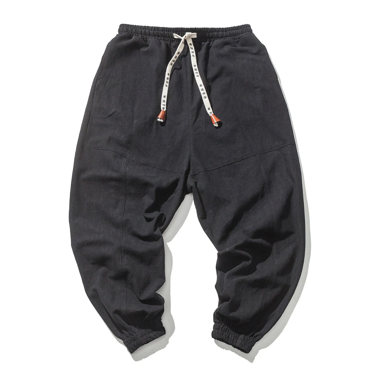 Men's cotton harem joggers in black with drawstring waist, two slant pockets, and tapered ribbed ankle.