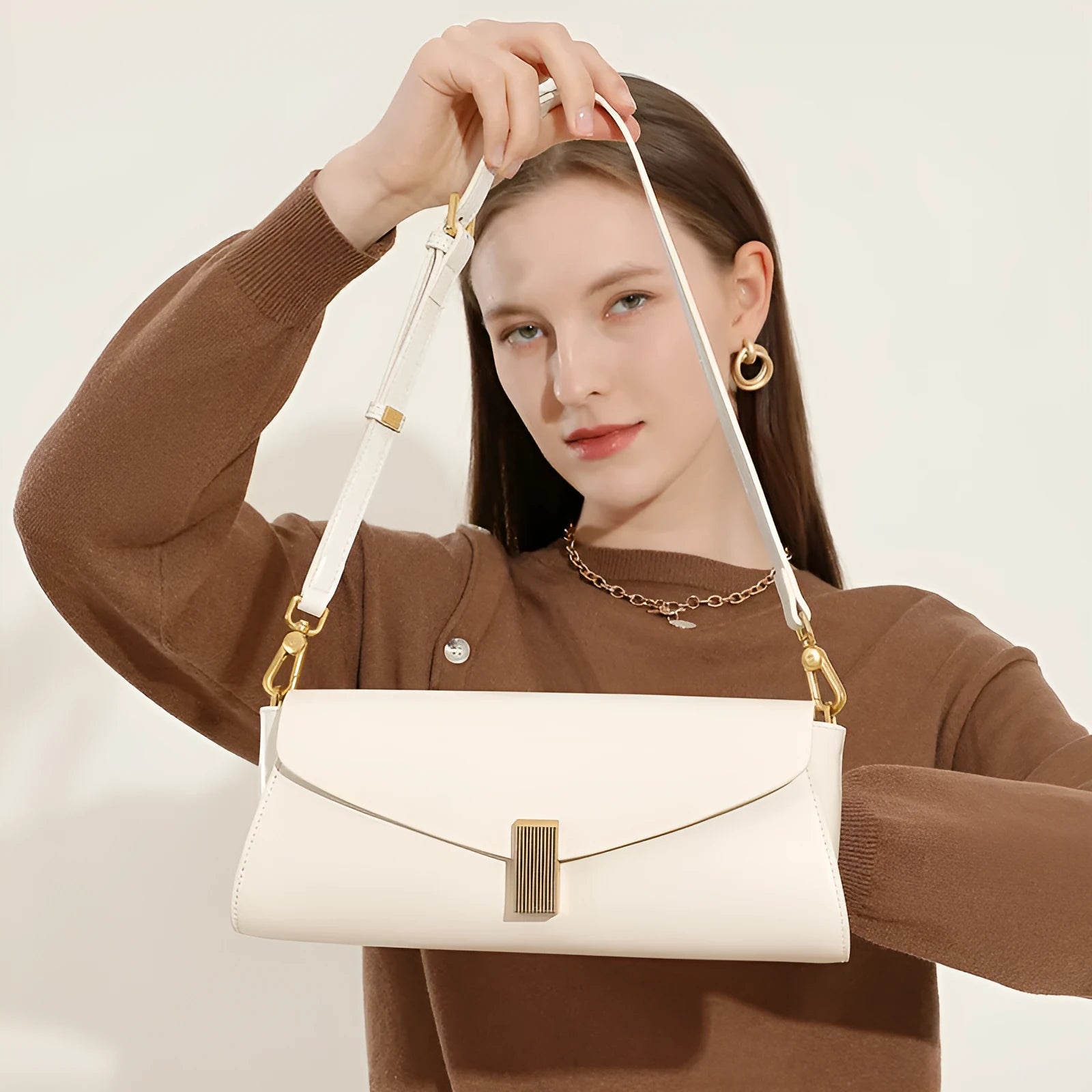 Women's leather cross-body bag with clamshell opening in milky white colour showing pillow-shaped design