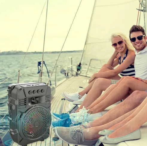 Black portable Bluetooth speaker with microphone and subwoofer on outdoor setting