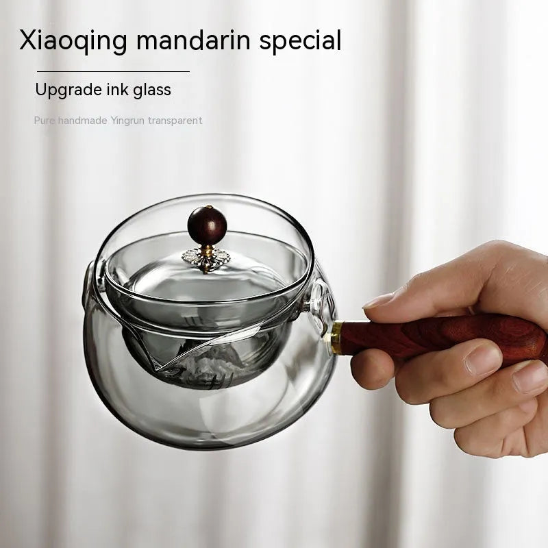 Transparent borosilicate glass teapot with wooden handle and infuser on rotary base