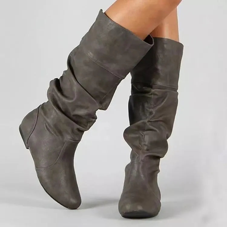 Women's black flat slip-on boots with round toe and high shaft on a white background.