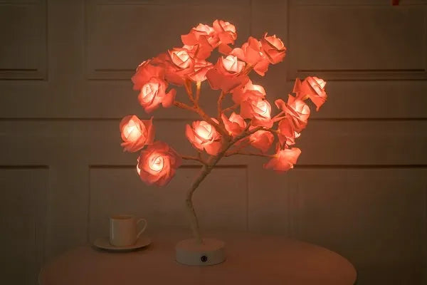 White and red rose flower LED table lamp with bonsai tree and garland lights on a table.