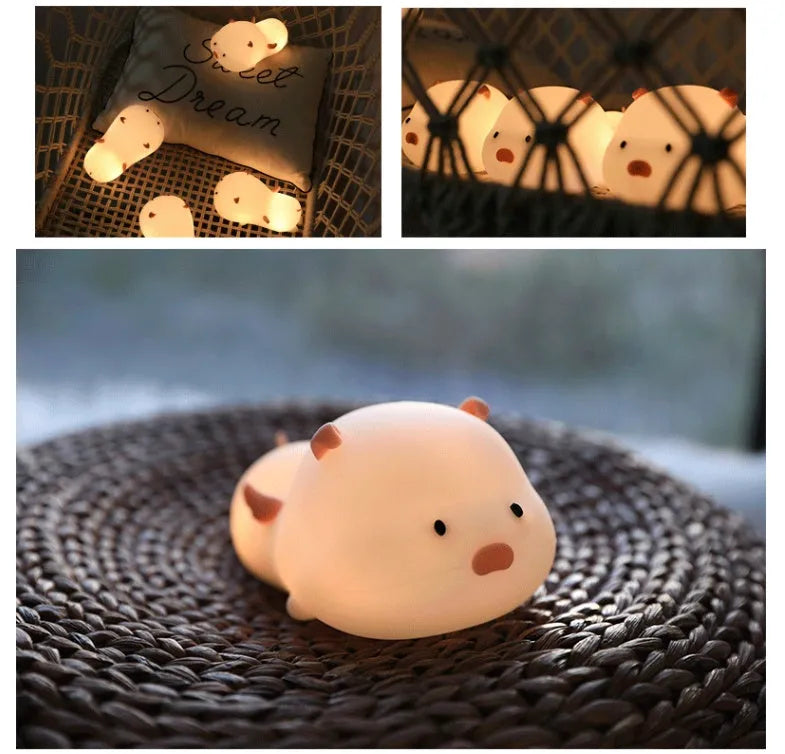 Blue rechargeable pig-shaped silicone night light with a sleeping design on a bedside table.