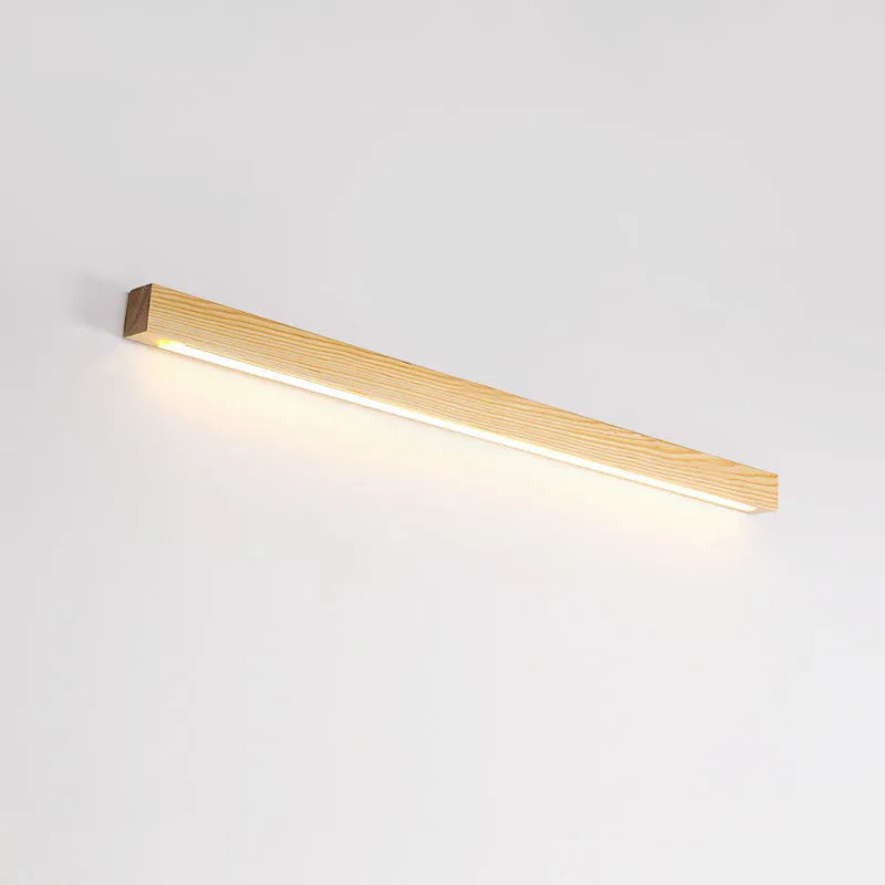 Long, slim walnut-coloured wooden wall lamp with integrated LED lighting on a plain wall.