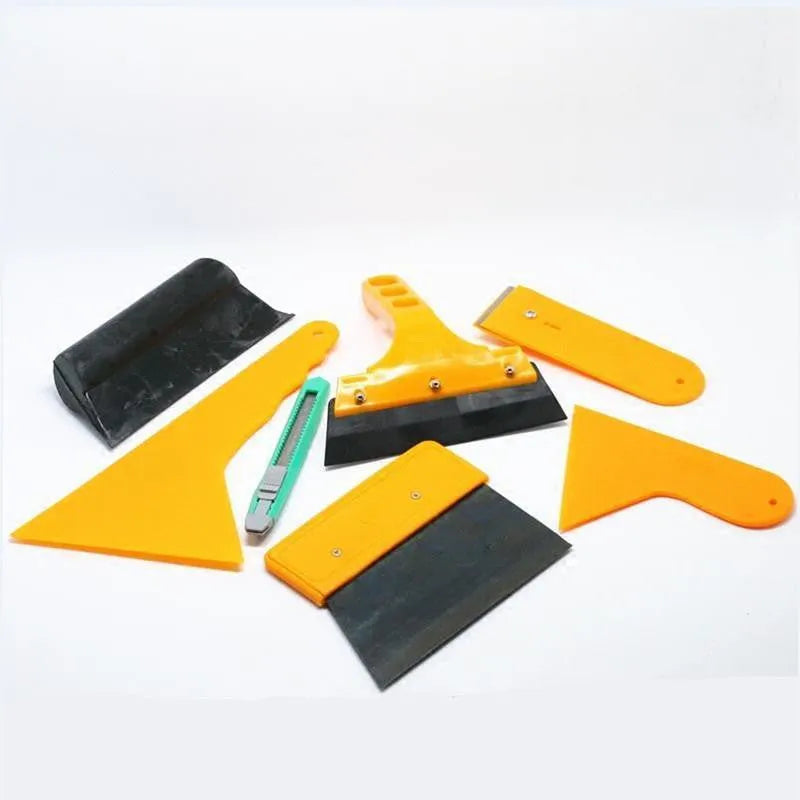 Seven-piece car film tool set including scrapers, knives, and a pressing block on a work surface.