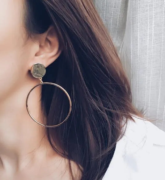 Large circle gold alloy hoop earrings with diamond-cut finish on white background