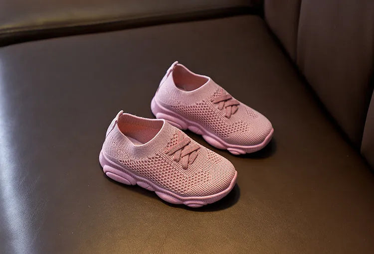 Children's white fabric lazy shoe with a non-slip rubber sole, shown on a foot.
