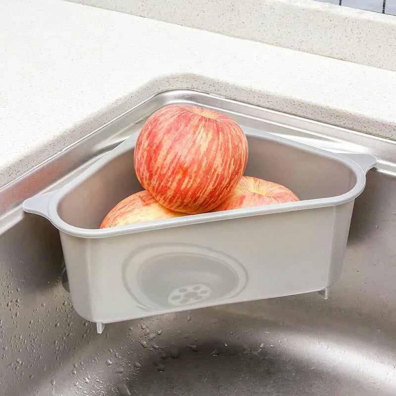 Triangular beige plastic kitchen sink storage rack with suction cup mount holding a sponge.