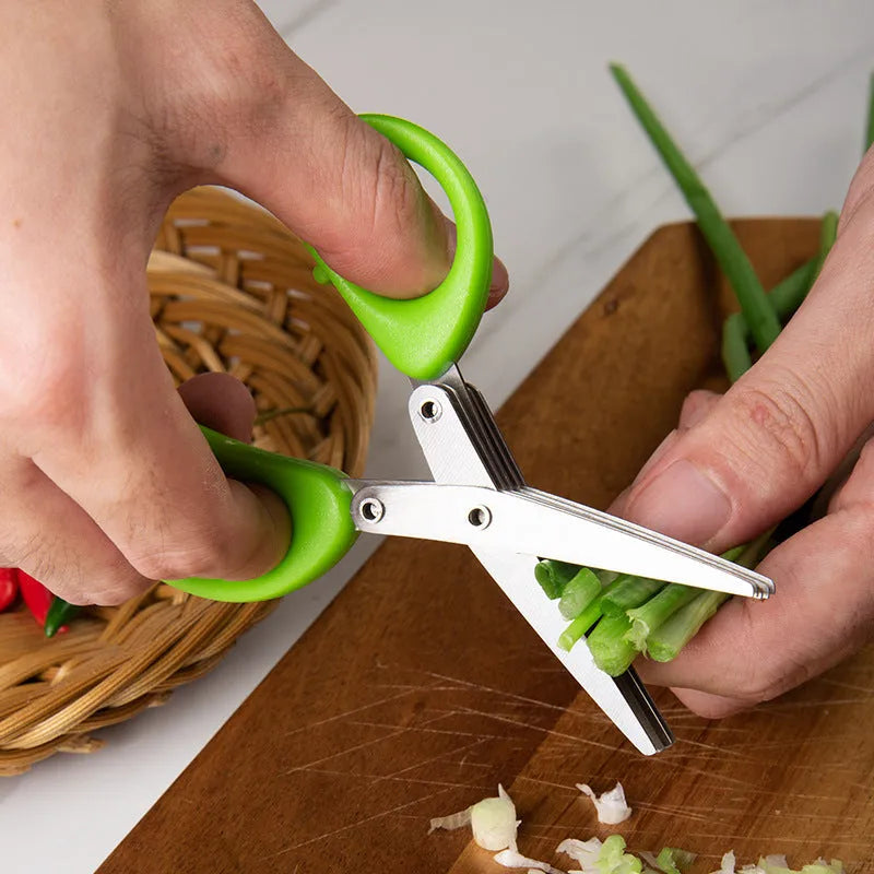 Stainless steel multi-blade kitchen scissors for cutting onions and herbs on a chopping board.
