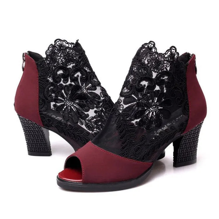Black lace gladiator sandals with a square high heel, zip closure, and peep toe on a woman's foot