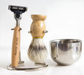 Men's manual shaving set with beech handle razor, bristle brush, stainless steel soap bowl, and metal stand
