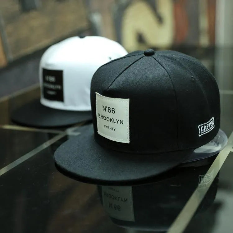 Leather snapback hat in black or white with adjustable fit, dome top, short brim, and curling eaves shape.