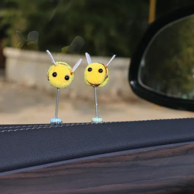 Small black and yellow cartoon bee car decoration with a spring, on a fur ball.