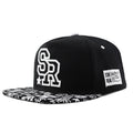 Black and white adjustable cotton baseball cap with embroidered lettering and dome crown.