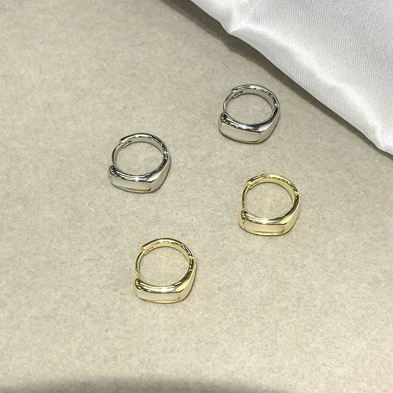 Four pairs of round buckle earrings in gold and silver metal finish on white background