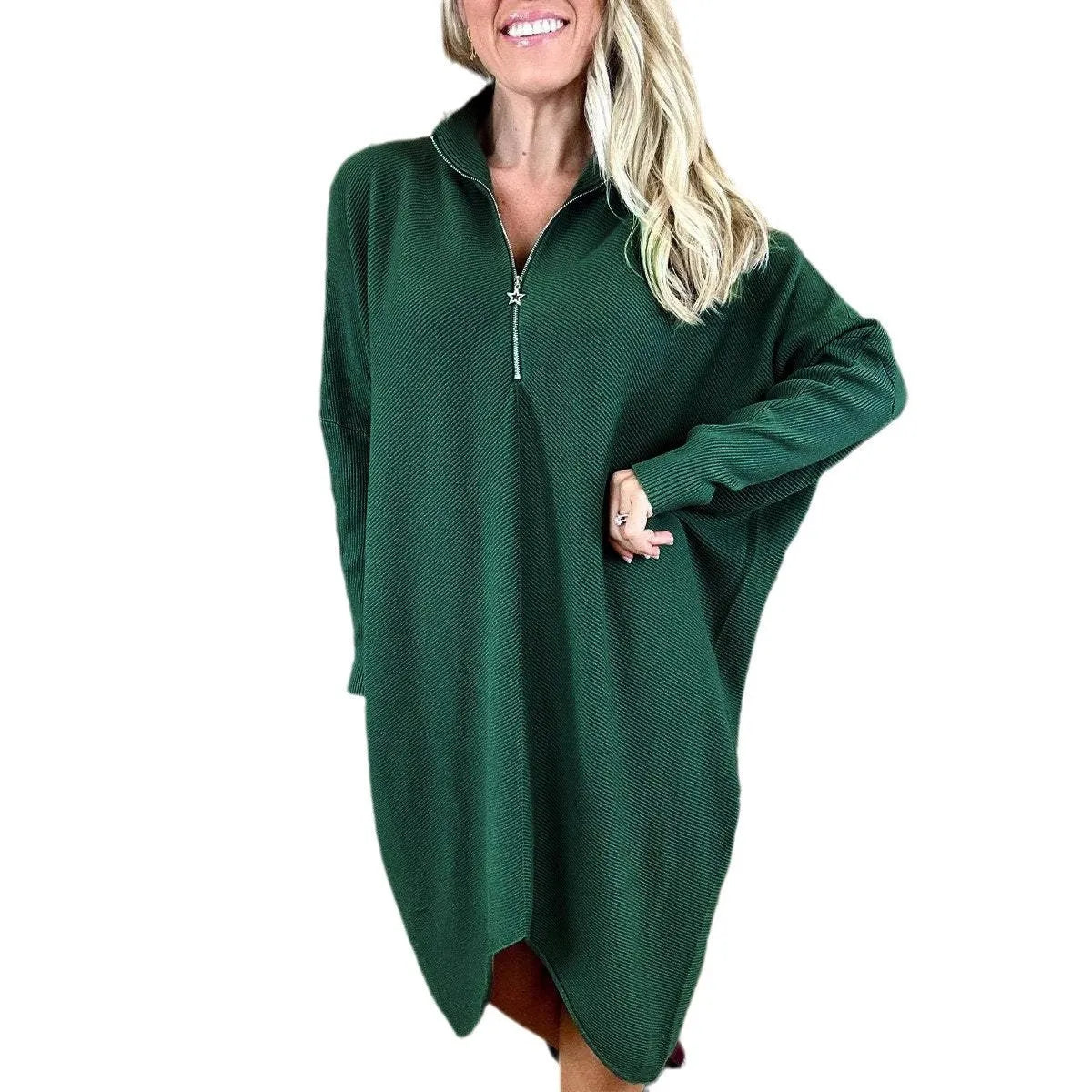 A woman wearing a solid dark green loose-fit knitted dress with raglan sleeves and a zipper detail.
