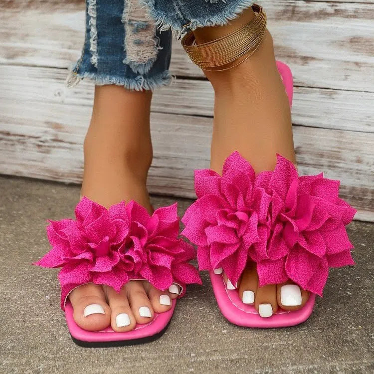 Women's flat flip-flops with flower detail on PU upper, available in apricot, black, white, red, and green