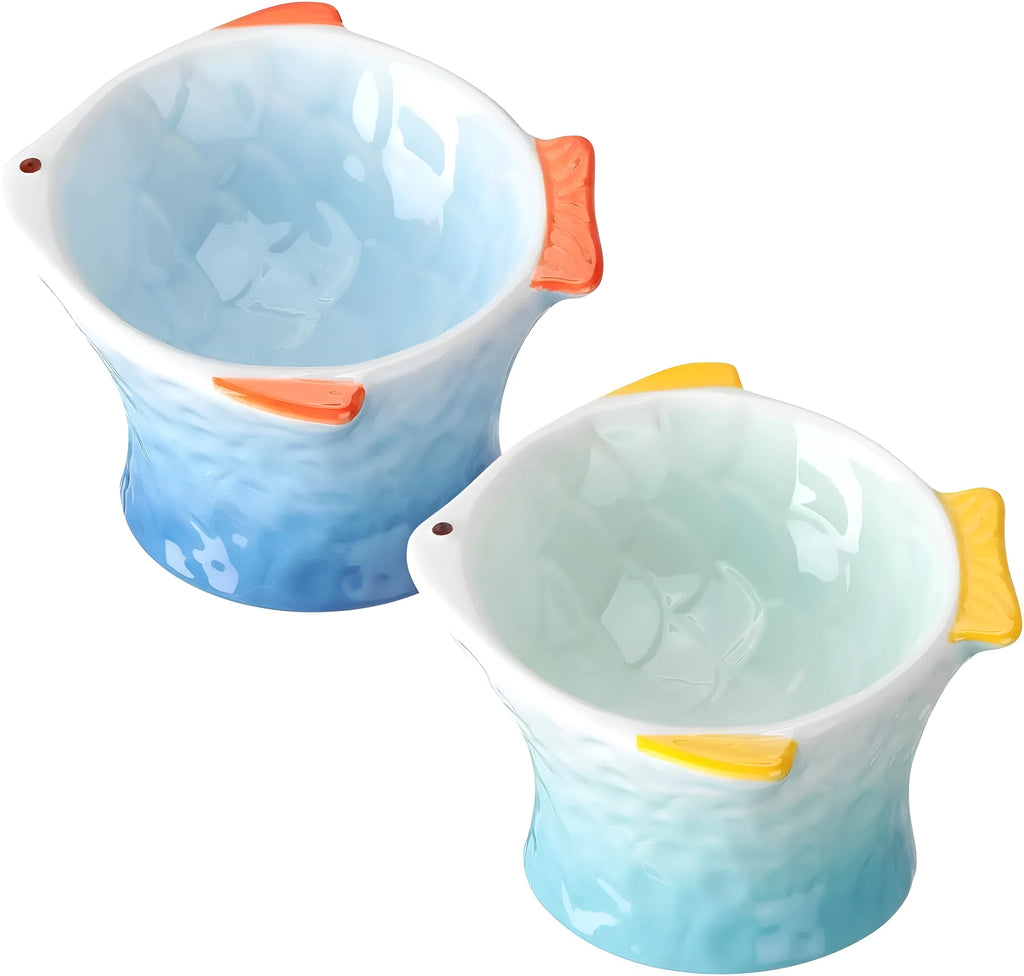Set of four blue fish-shaped ceramic cat bowls on a table, showing elevated shallow design and tilt angle.