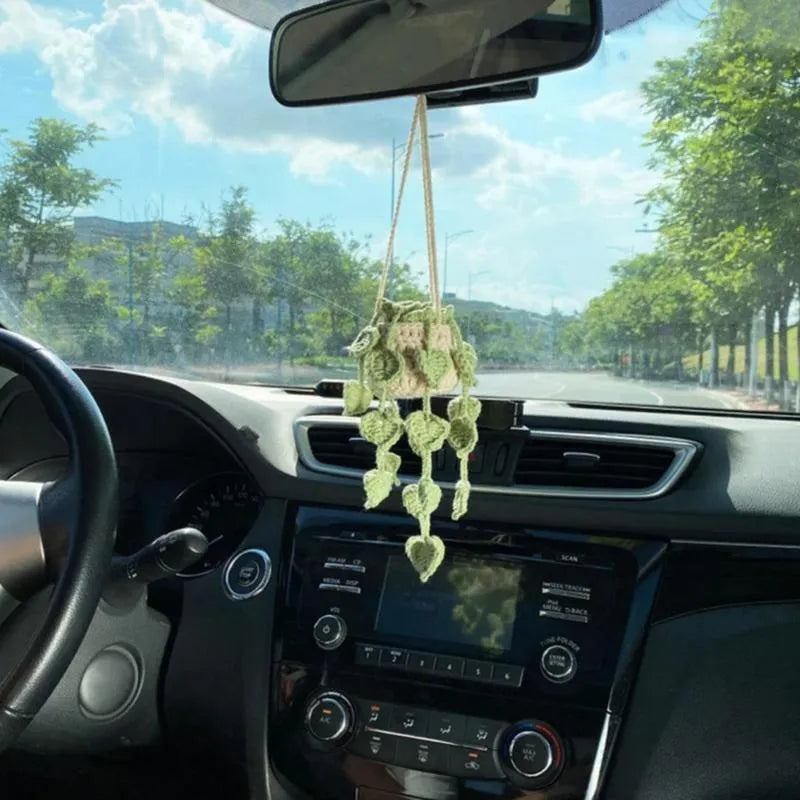 Green knitted wool car plant hanger with white rope, holding a small pot.