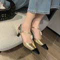 Gold women's stiletto heel shoe with flower buckle and pointed toe on a white background.