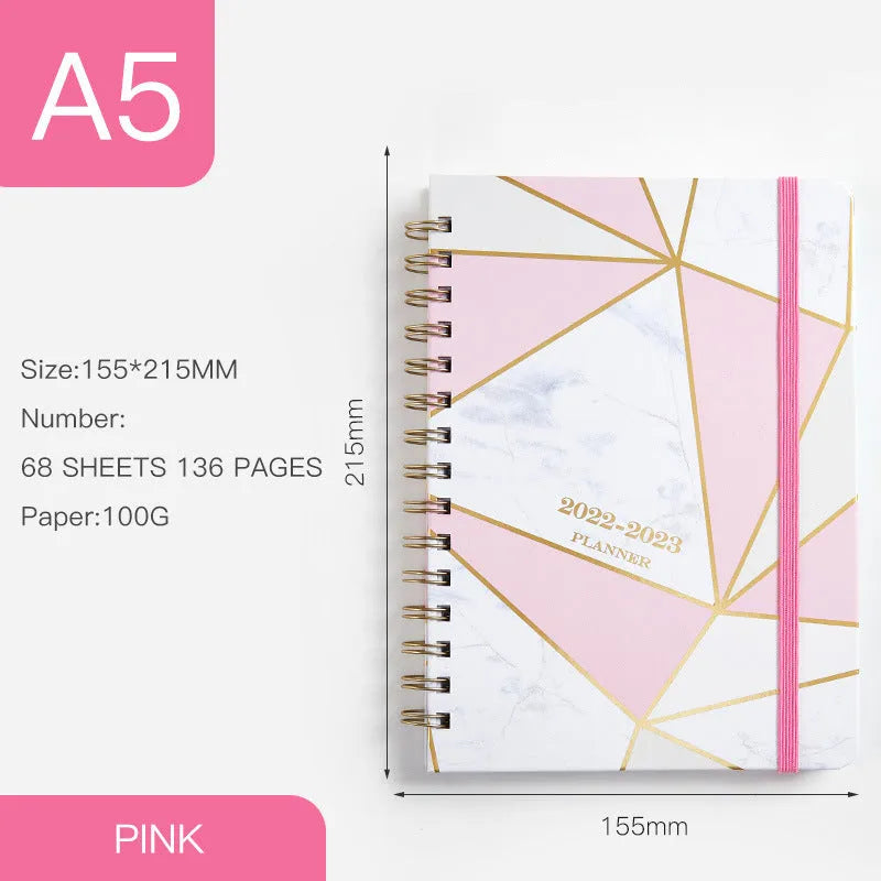 A5 spiral-bound notebook with a colourful floral design cover, lying open on a table.
