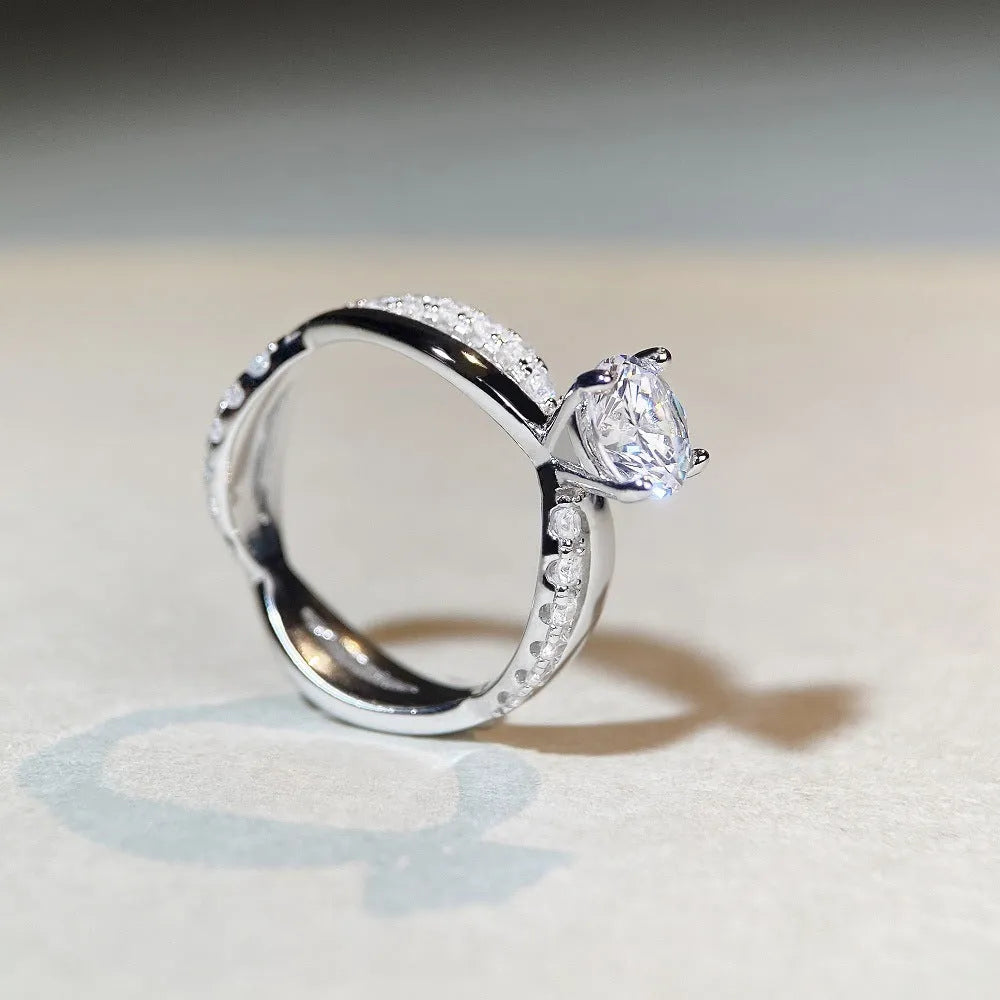 Close-up of a silver geometric ring with a twisted band and a 1-karat moissanite stone in a four-claw setting.