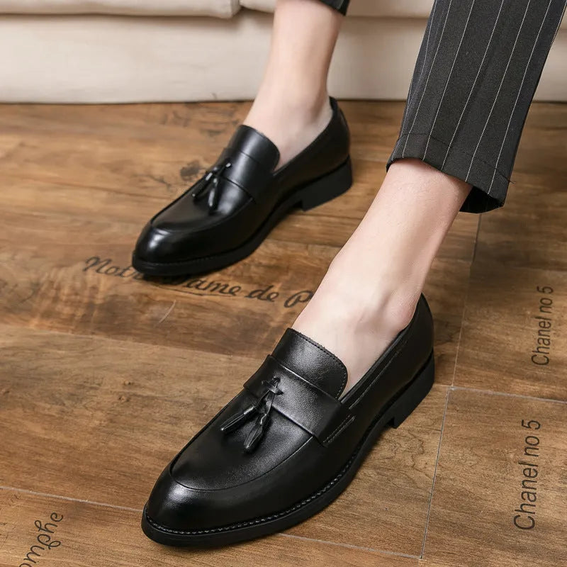 Men's black slip-on business casual shoe with tassel detail and rubber sole.