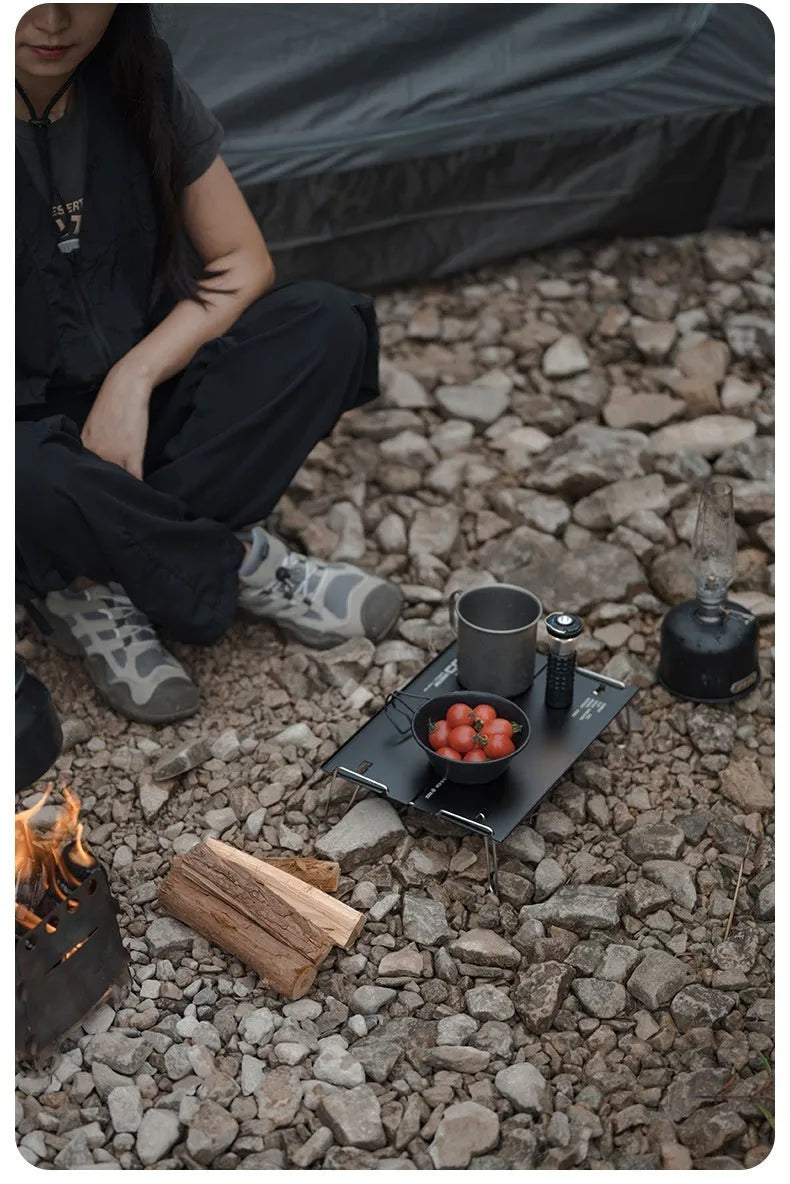Aluminium alloy camping folding table shown in a folded position, available in black or grey colour.