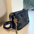 Small square crossbody bag in Oxford cloth, shown in a solid colour on an adjustable strap.