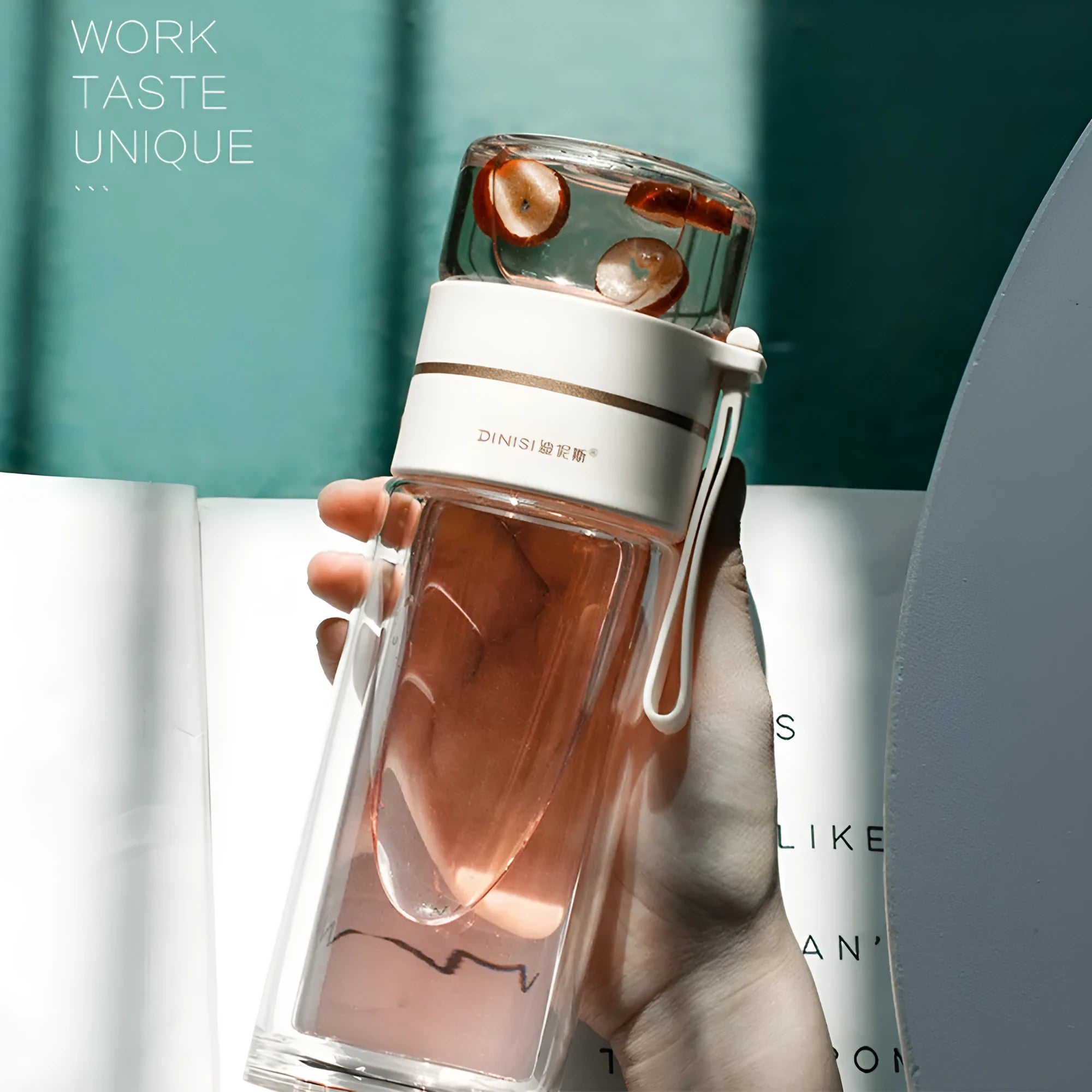 Green double-wall glass water bottle with tea infuser, stainless steel filter, and rope handle on a wooden table.