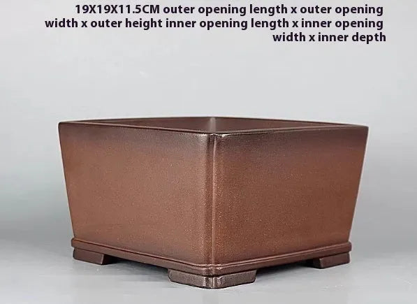 Handmade brown antique classical purple clay ceramic flower pot on a windowsill.