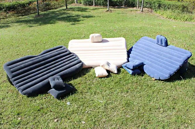 Inflatable car bed with flocking material shown in black colour, folded beside pillows and storage bag