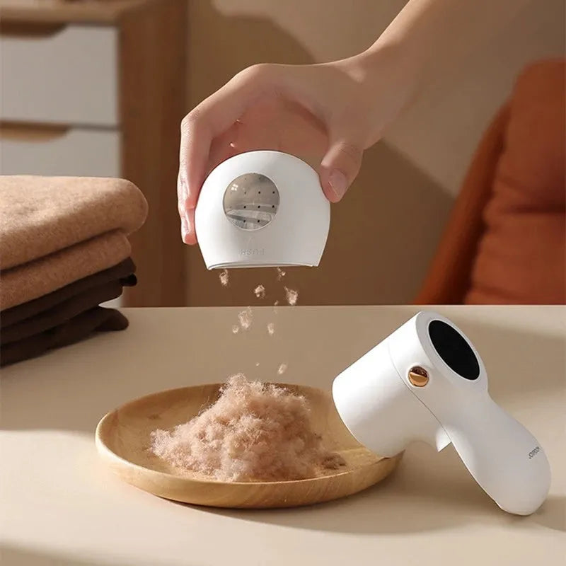 White electric lint remover with LED display, USB port, and stainless steel cutter head on a fabric background.