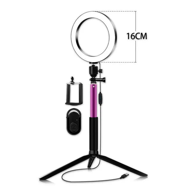 Black 20cm LED ring light kit with tripod, selfie stick, and phone clip on a desk